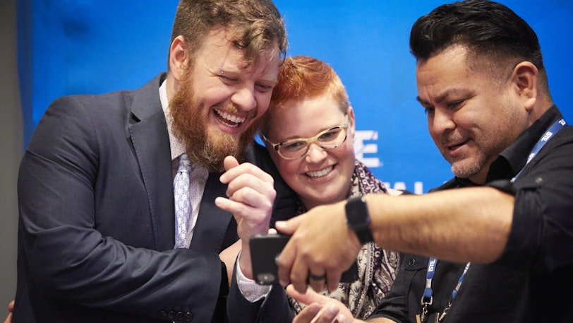 A small group of educators smiling as they look at a cellphone.